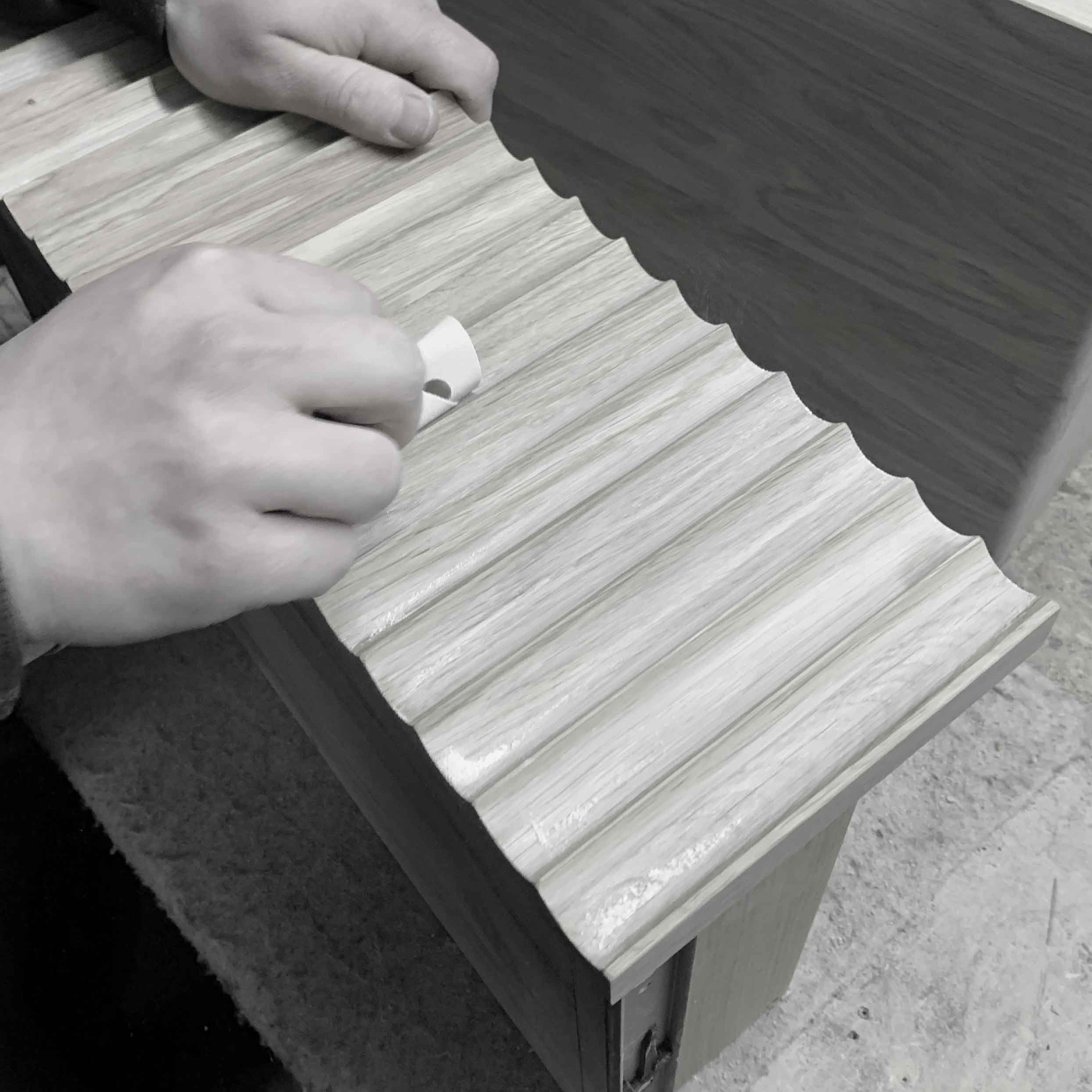 Person applying adhesive to a wooden surface