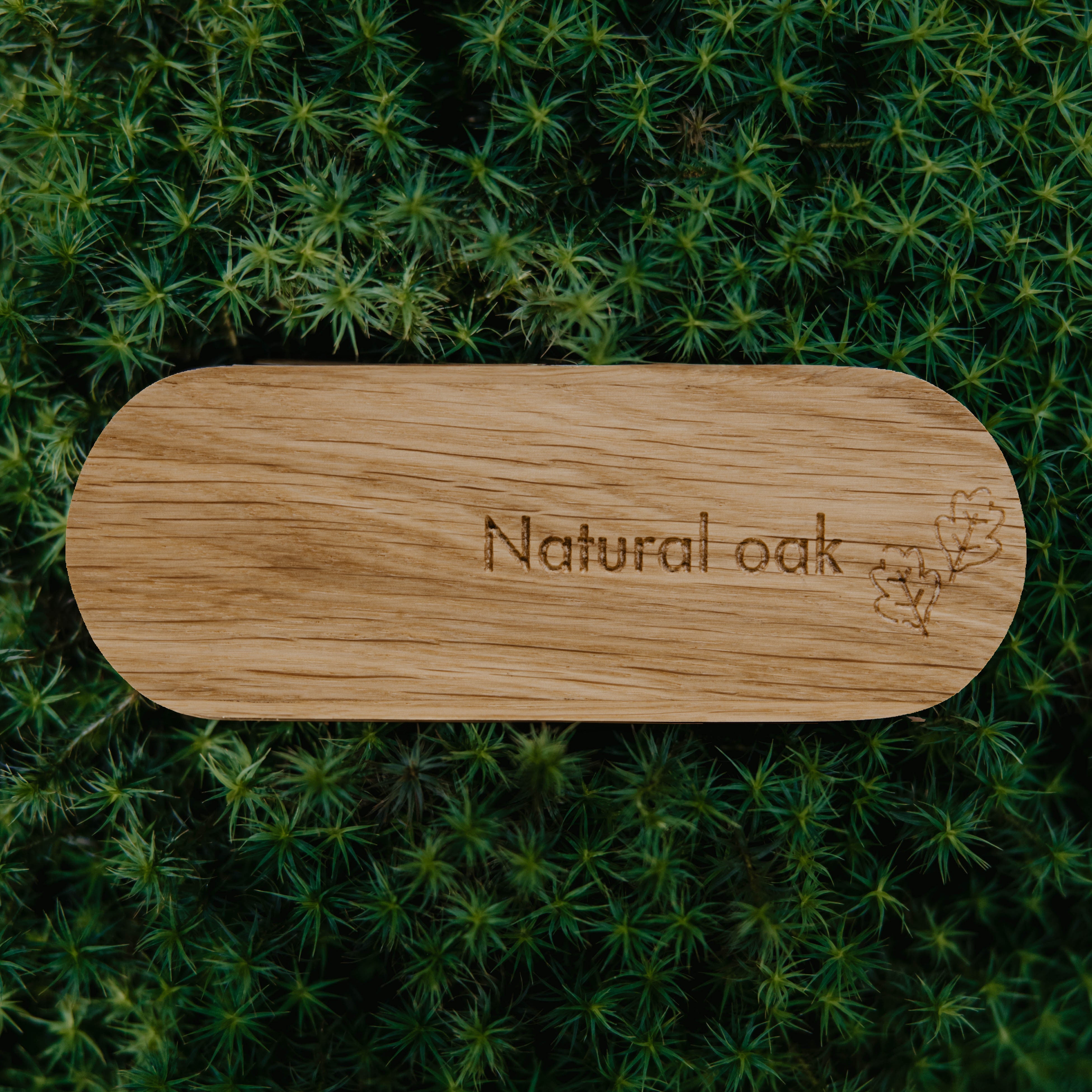 Wooden cutting board with 'Natural oak' engraving on a green moss background
